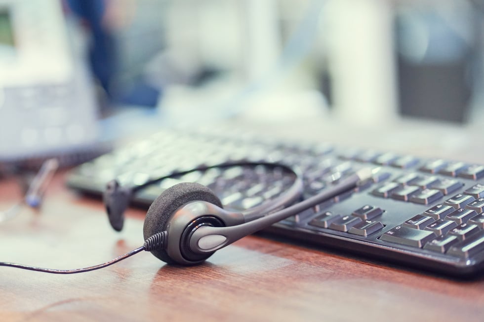 close up focus on call center headset device at VOIP system laying on keyboard computer at office desk for hotline telemarketing and network operation concept